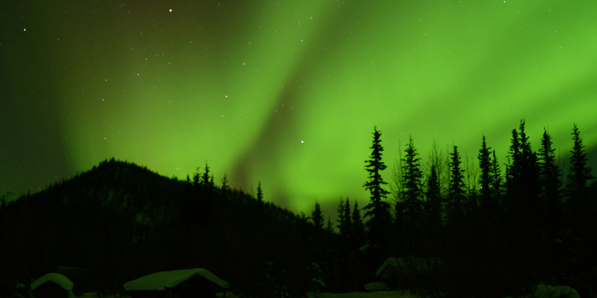 What causes the Northern Lights? 3 Lights dance above a cabin