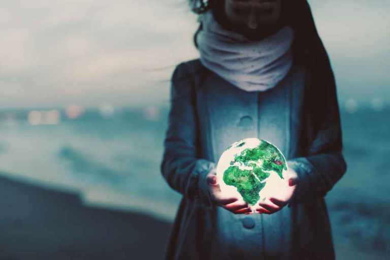 Image of a woman holding the Earth in her hands on a beach for Gondwana Ecotour's post on Earth Day!