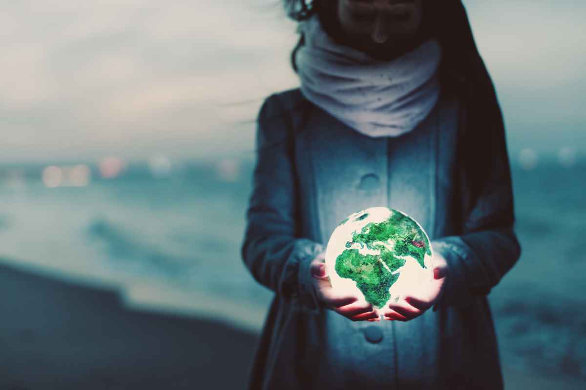 Image of a woman holding the Earth in her hands on a beach for Gondwana Ecotour's post on Earth Day!