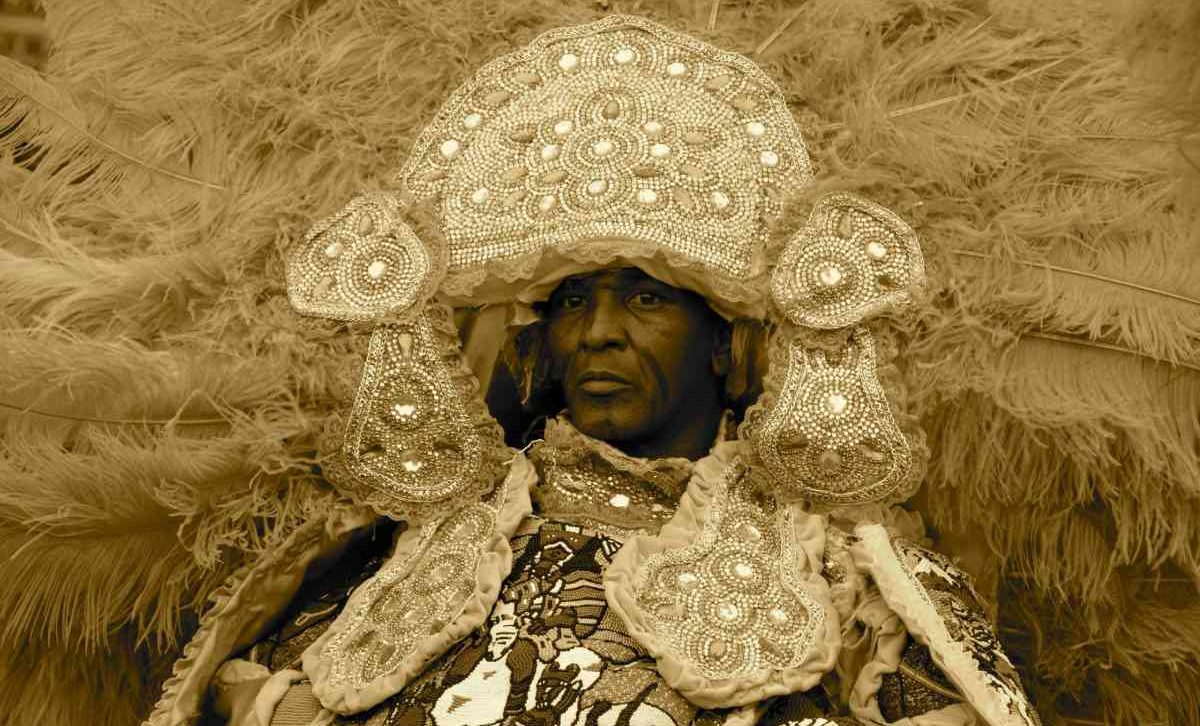 A person wears traditional festival costume of a large beaded headers with long feather plumes 